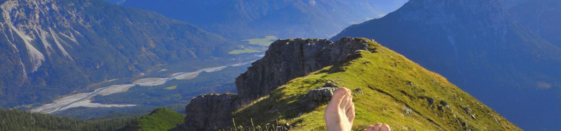 Rast ohne Schuhe auf einem Grat mit Blick auf die Gipfel - Alpen