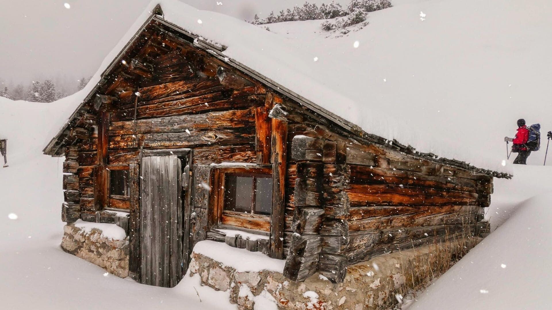 Chalet de bois sous la neige et randonneur - Dolomites - Italie