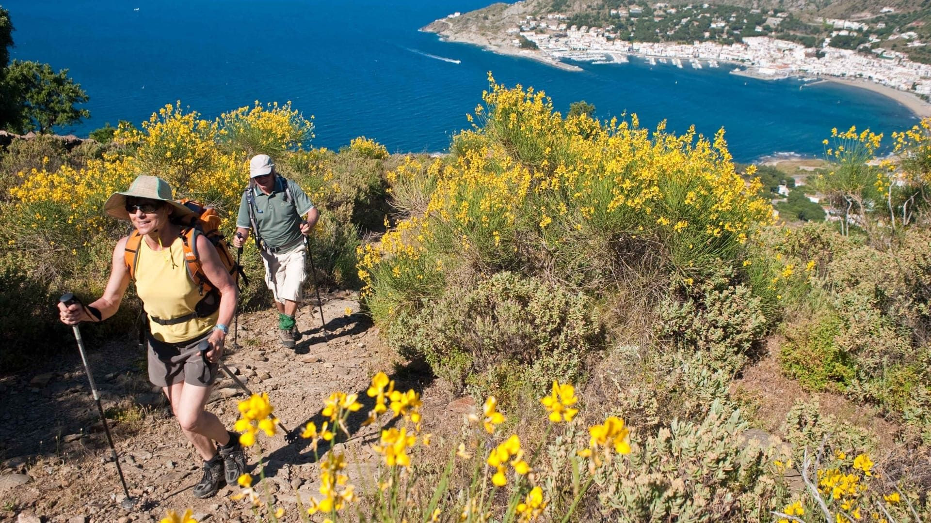 Wanderer auf einem blühenden Küstenpfad oberhalb des Hafens - Costa Brava - Spanien