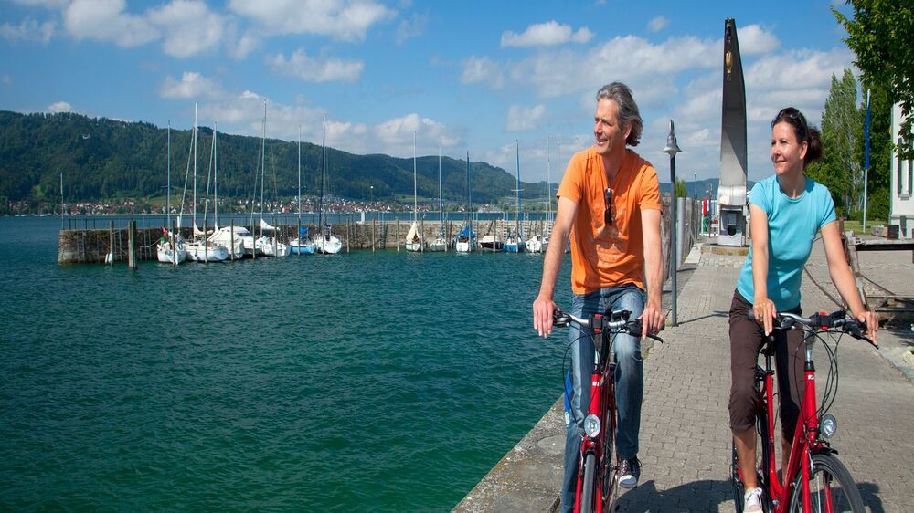 Paar fährt mit dem Rad am Hafen des Bodensees entlang - Deutschland