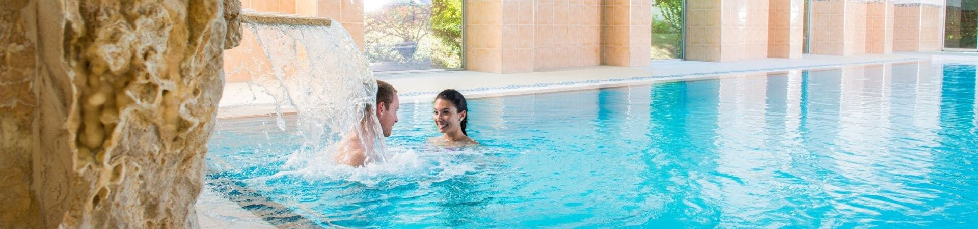 Couple dans une piscine de spa sous une cascade - Hôtel de luxe