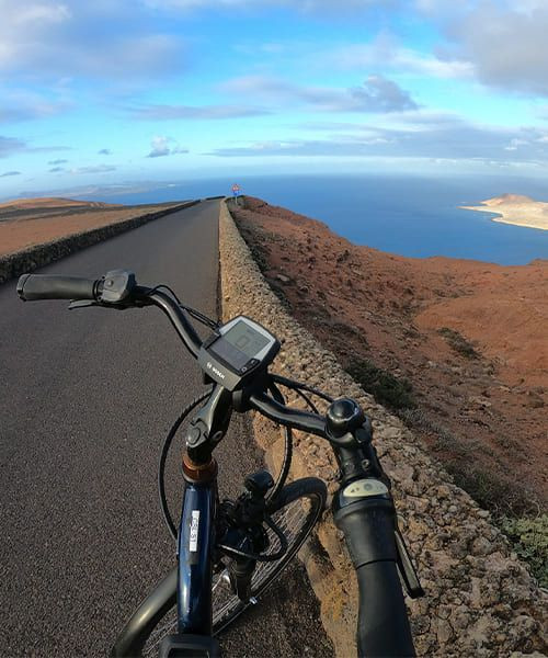© David Praire Radfahrer auf den Vulkanstraßen von Lanzarote oberhalb des Meeres - Kanaren - Spanien