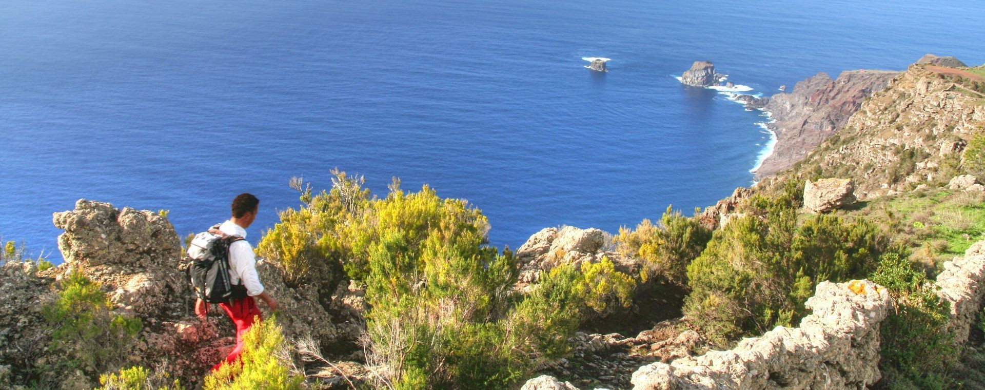 Wanderin auf dem Küstengrat mit Blick auf die Roques de Salmor - El Hierro - Kanarische Inseln - Spanien
