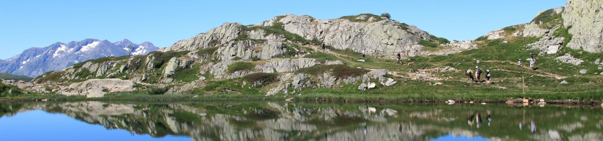Wanderer an einem Bergsee mit Spiegelung der Gipfel - Französische Alpen - Frankreich