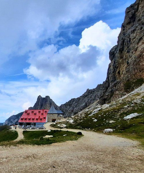 Berghütte mit rotem Dach am Fuß der Dolomitenklippen - Italien