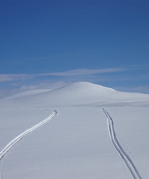 Skispuren über das verschneite Plateau zu einer weißen Kuppel