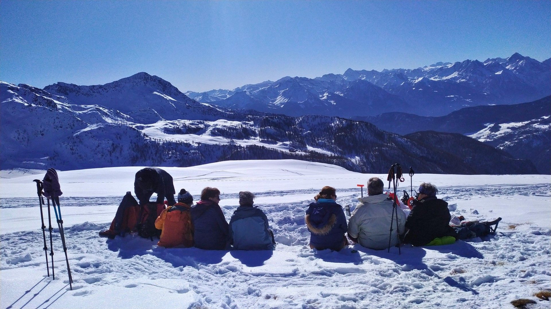 Schneeschuhgruppe bei einer Rast mit Blick auf verschneite Gipfel - Italienische Alpen - Italien