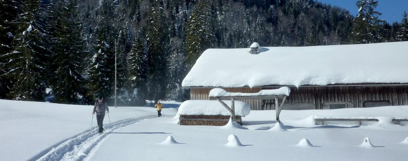 Schneeschuhwanderung nahe einer verschneiten Scheune - Bregenzerwald - Österreich