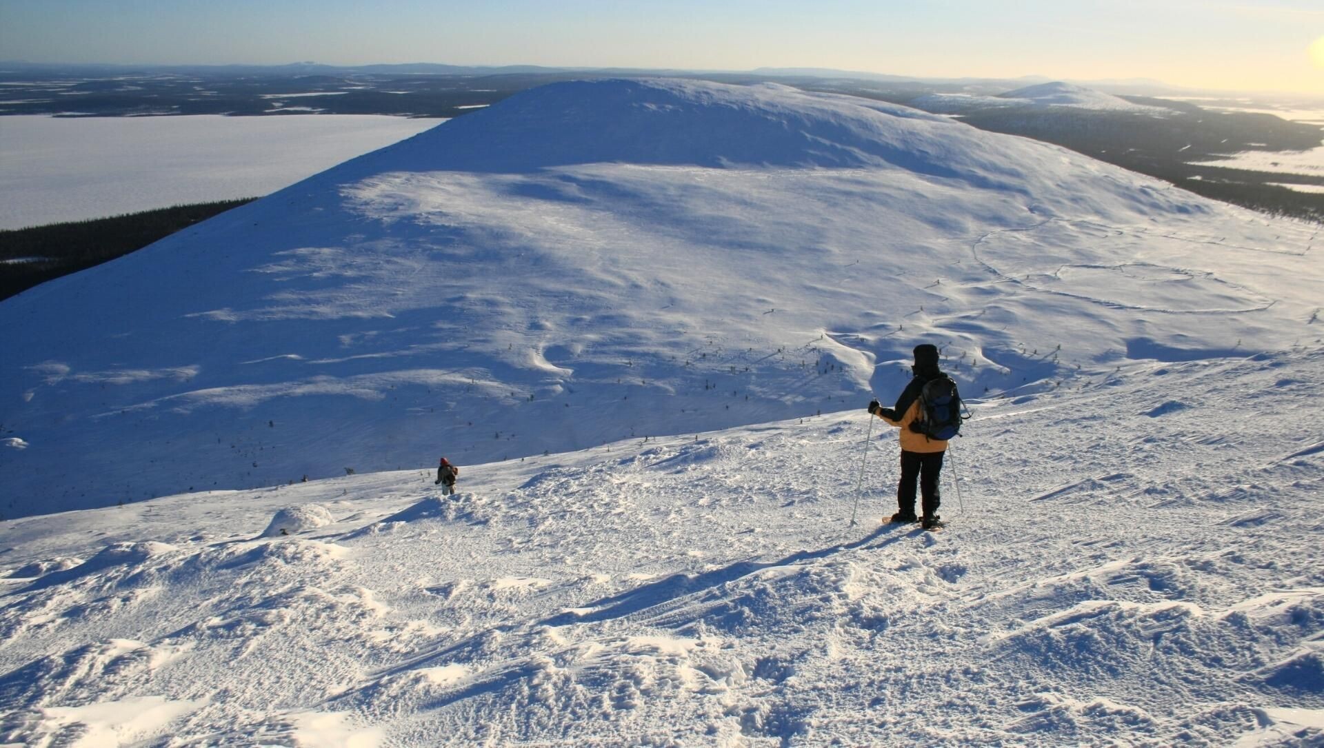 Schneeschuhwanderung auf einem verschneiten Hügel bei Sonnenuntergang - Lappland - Finnland