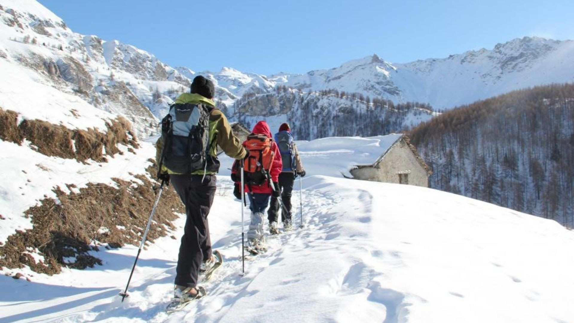 Schneeschuhwanderer auf dem Weg zu einem verschneiten Weiler - Italienische Alpen - Italien