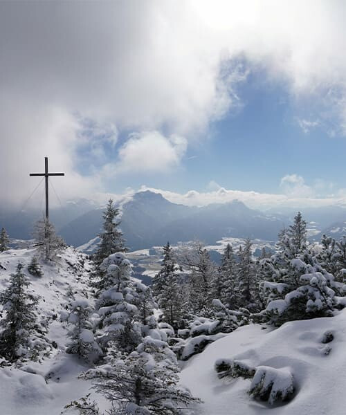 Gipfelkreuz und verschneite Berge im Winter - Alpen