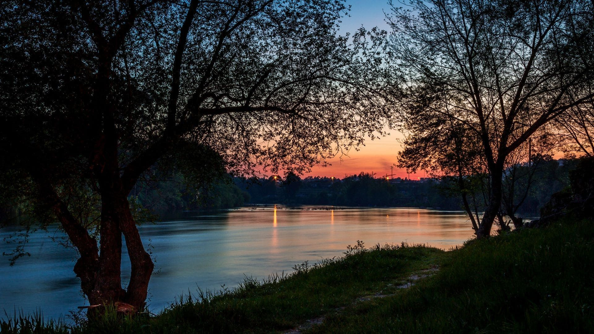 Sonnenuntergang über einem von Bäumen gesäumten Fluss - Portugal