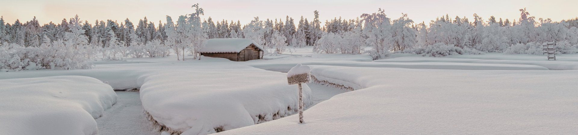 Cabane en bois dans un paysage hivernal enneigé - Laponie